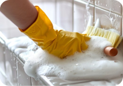 Gloved hand scrubbing a foamy surface with a brush